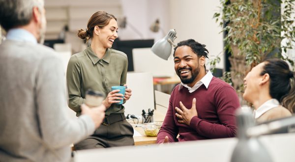 Multi-ethnic group of entrepreneurs laughing while talking to each other on a break in the office.
