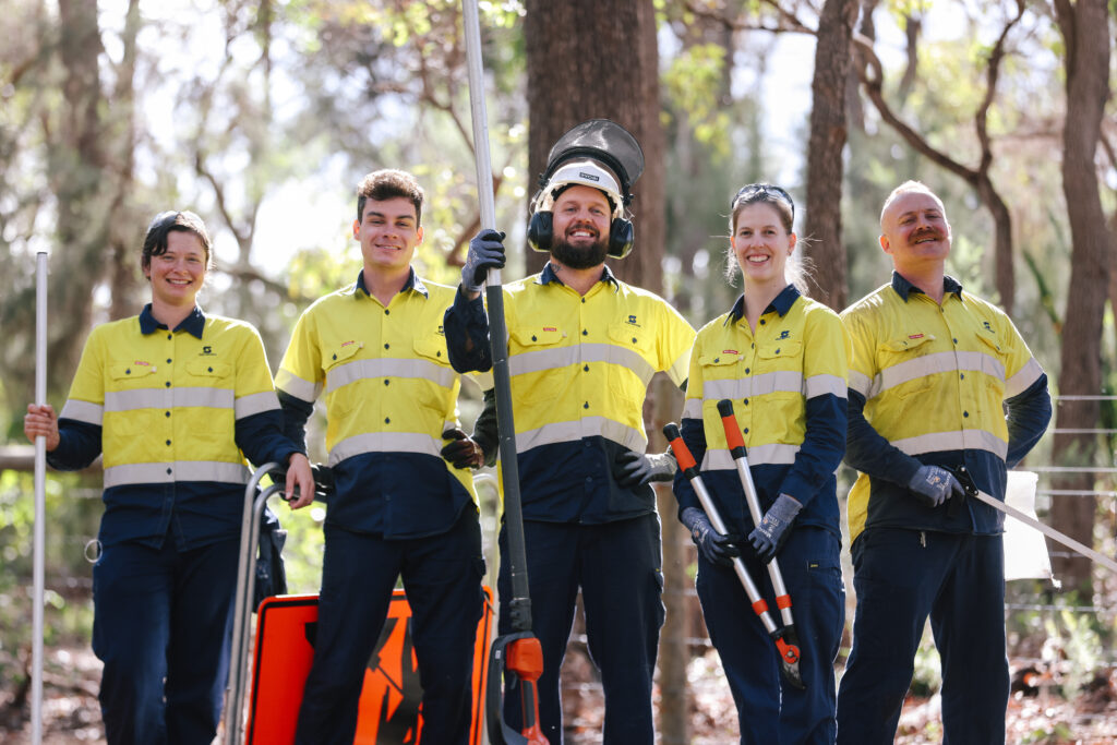 Five workers in hi-visibility clothing smiling at the camera.