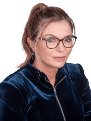 Dee Madigan, a woman wearing a navy blue blazer and brown glasses