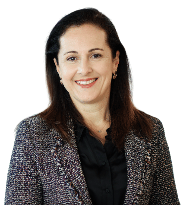 Niki Kesoglou, wearing a black and grey suit, with brown, straight hair.