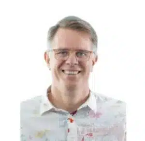 Man wearing a button up white top and wearing orange glasses